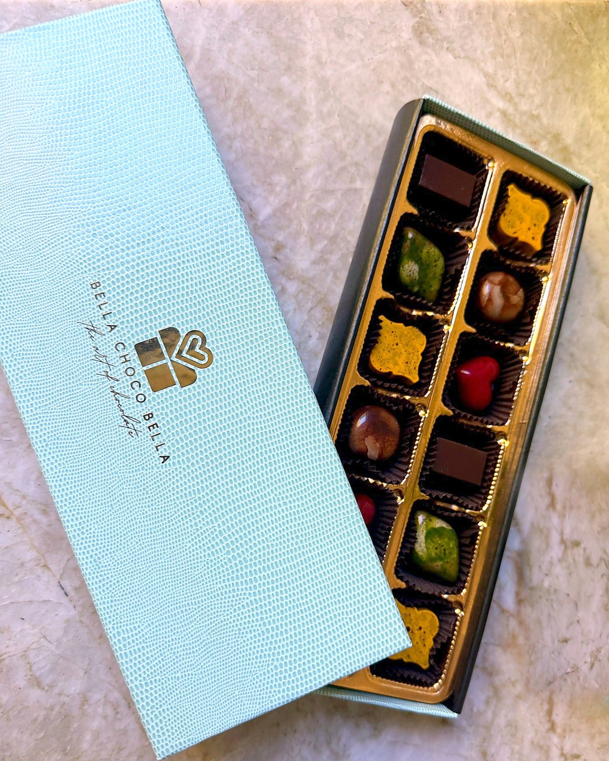 Overhead view of the Tiffany Blue 18-piece box with gold foil logo and hand-painted bonbons