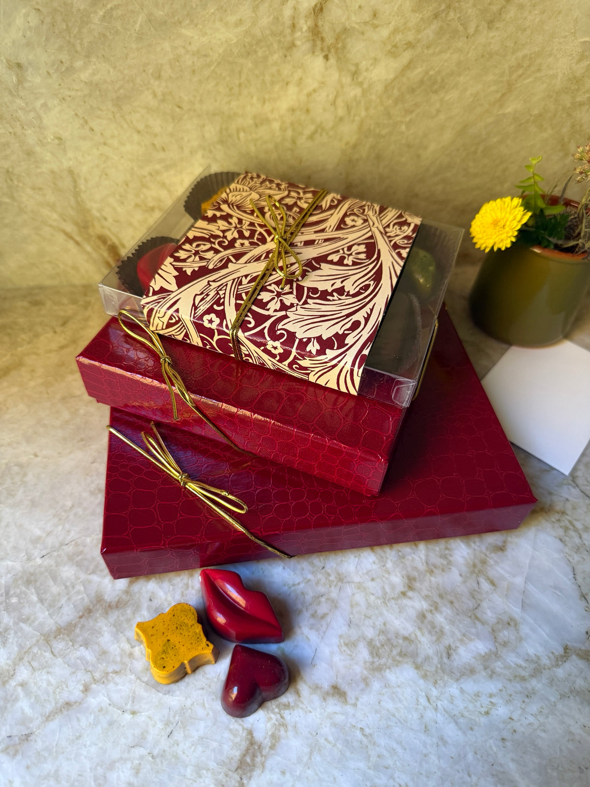 Grand Celebration Tower chocolate gift set: red croco-embossed Bella Choco Bella boxes tied with gold cord, topped with a botanical-banded box of bonbons