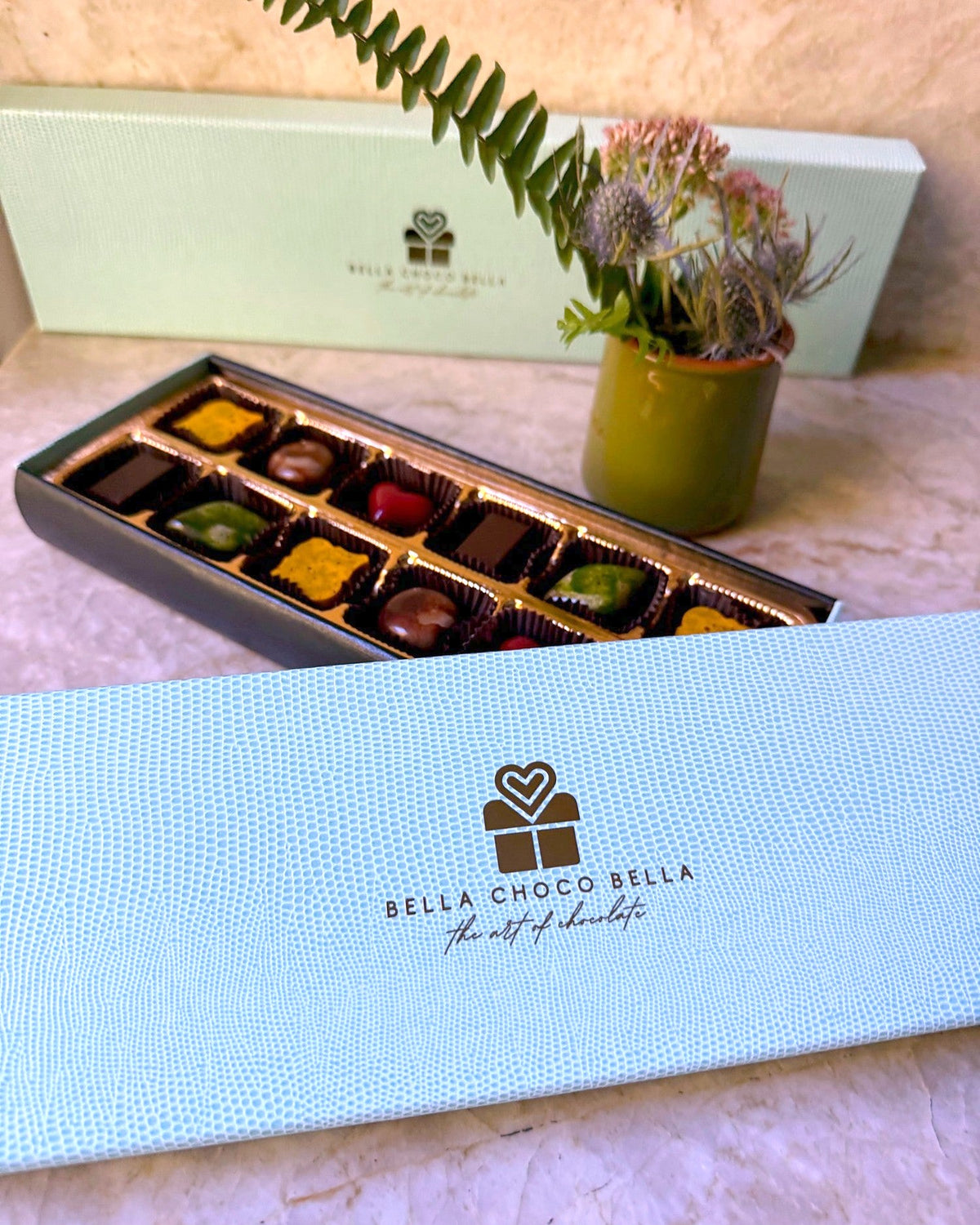 Tiffany Blue textured lid with Bella Choco Bella logo beside the open 12-piece tray